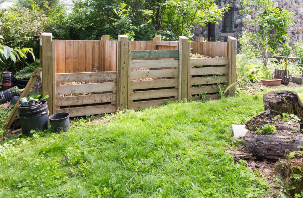 Large wooden compost bins in a backyard garden for sustainable waste recycling.
